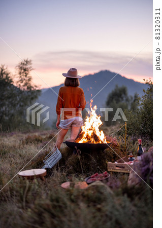 Woman at picnic with bonfire in the mountains 81320311