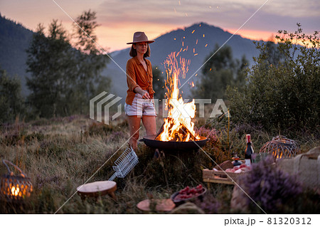 Woman at picnic with bonfire in the mountains Woman at picnic with bonfire in the mountains 81320312