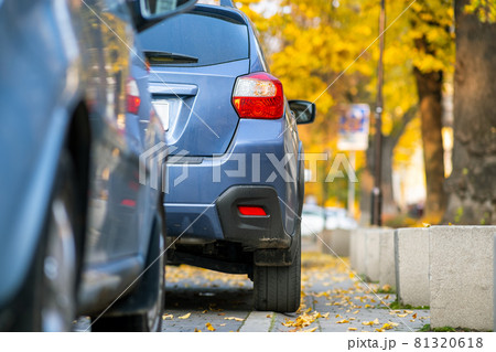 Cars parked in a row on a city street side on bright autumn day. 81320618