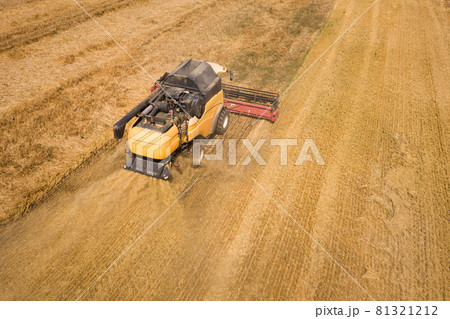 Aerial view of combine harvester harvesting large ripe wheat field. Agriculture from drone view. Aerial view of combine harvester harvesting large ripe wheat field. Agriculture from drone view. 81321212
