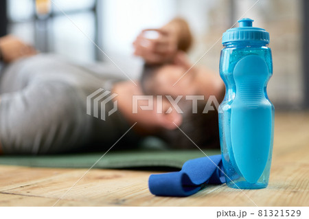 Young man lying on the floor with bottle of water and fitness band 81321529