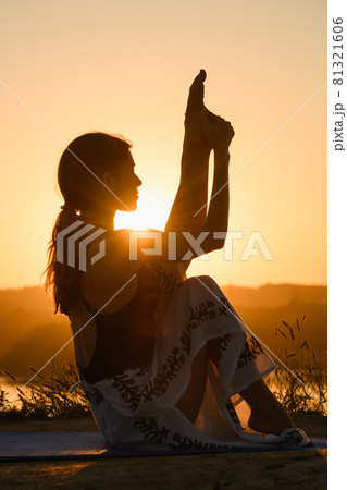 Female silhouette stretching at warm sun light 81321606