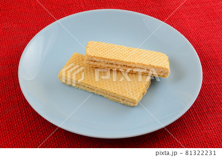 Two taro cream wafer cookies on blue snack plate on red background Two taro cream wafer cookies on blue snack plate on red background 81322231