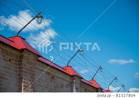 Barbed wire on the fence of the prison against the blue sky Barbed wire on the fence of the prison against the blue sky 81327804