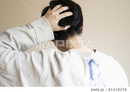 頭を触る後ろ姿の男性の写真素材