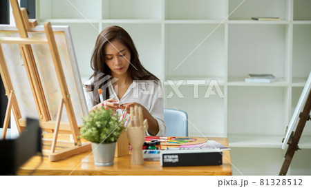 Young gorgeous female artist looking at oil colour for her art work 81328512