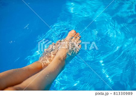 Summer vacation concept. The legs of a young woman on the background of the blue water of the pool. Swimming in the pool. Relaxation, sunbathing and joy. 81330989