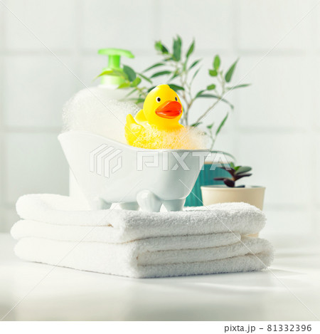 A miniature bubble bath, yellow rubber duck and white towels on bathroom countertop, children bath accessories, baby care 81332396
