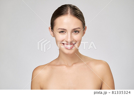 Beautiful Young Woman with Clean Fresh Skin standing over light grey background 81335324