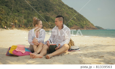 The cheerful love couple holding and eating slices of watermelon on tropical sand beach sea. Romantic lovers two people spend summer weekend. 81339563