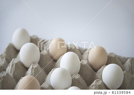 White and dark eggs in an egg carton on a white background. 81339584