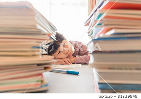 たくさんの教科書と勉強に疲れている小学生の子供の様子 81339949