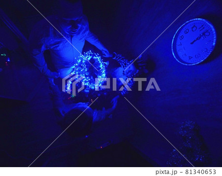 The family fast and fanny decorates the Christmas tree. Top view. Time on the clock is 23.45 on wall. Happy dad, mom, daughter are run around tree. The family fast and fanny decorates the Christmas tree. Top view. Time on the clock is 23.45 on wall. Happy dad, mom, daughter are run around tree. 81340653