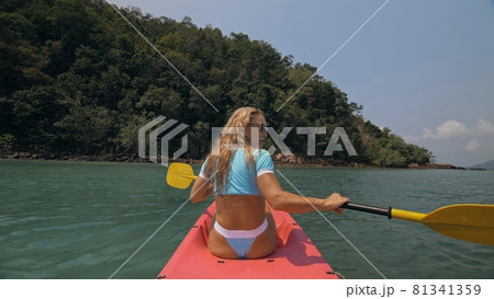 Sportive woman rows pink plastic canoe along sea water. Sportive woman rows pink plastic canoe along sea water. 81341359
