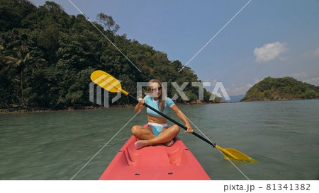 Sportive woman rows pink plastic canoe along sea water. 81341382