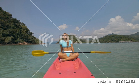 Sportive woman rows pink plastic canoe along sea water. 81341383