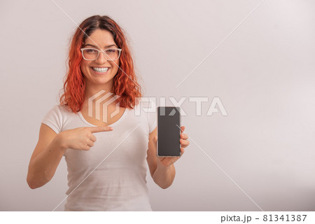 A Caucasian woman points to a smartphone with a blank screen on a white background A Caucasian woman points to a smartphone with a blank screen on a white background 81341387
