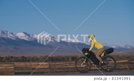 The woman travel on mixed terrain cycle touring with bikepacking. The traveler journey with bicycle bags. Sport tourism bikepacking. 81341991
