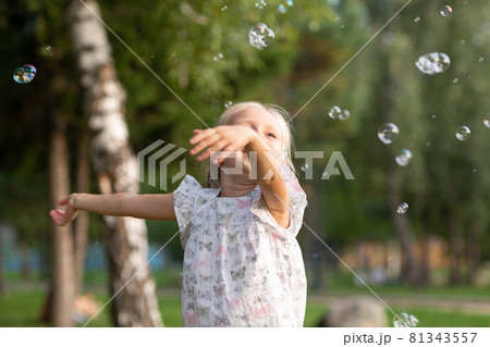 Little cute girl in the summer park blowing bubbles and having fun 81343557