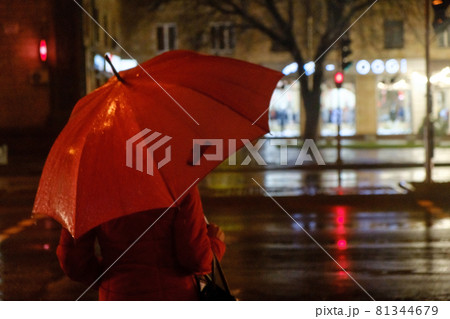 Rainy evening. A woman silhouette with umbrella and running traffic with drops of rain. Autumn time. 81344679