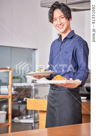 料理を運ぶエプロン姿の若い男性　料理男子イメージ 81351092