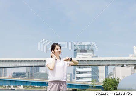 歩きながらスマートウオッチで健康状態を確認する女性 歩きながらスマートウオッチで健康状態を確認する女性 81353756