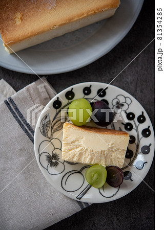 皿に乗ったカットしたチーズケーキとシャインマスカット、巨峰 81354286