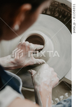 Creating a jar or vase of white clay close-up. Woman hands making clay jug. 81356931