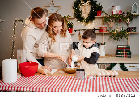 little boy pours milk himself. family together prepares dishes for the new year little boy pours milk himself. family together prepares dishes for the new year 81357112
