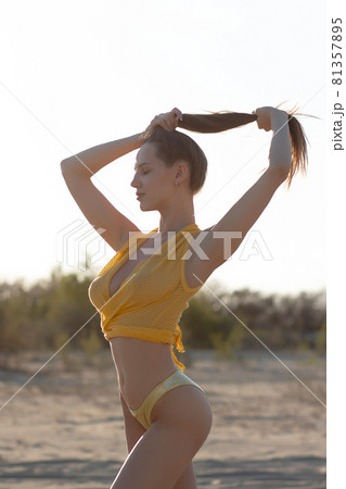 Sensual young female enjoying sunset on sandy coast Sensual young female enjoying sunset on sandy coast 81357895