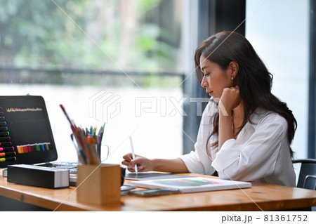 Peaceful female artist working with digital tablet at modern workplace. 81361752