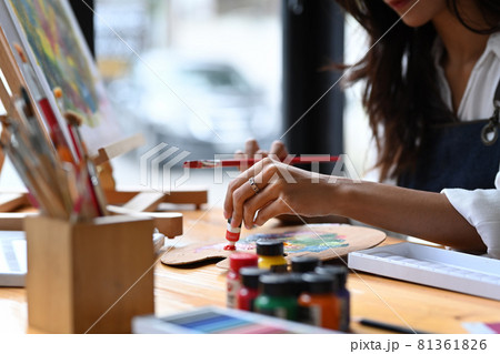 Female artist holding painting brush and mixing color on palette. 81361826