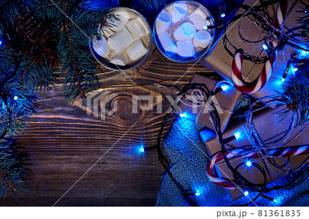 Christmas hot drink. Cocoa with marshmallow, garland and spruce branches on a wooden background. Top view 81361835