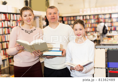 parents and girl standing with stack of books 81362489