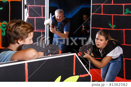 Children with parents holding laser guns during laser tag game in dark labyrinth Children with parents holding laser guns during laser tag game in dark labyrinth 81362562