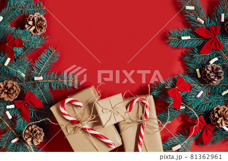 Christmas composition of pine cones, spruce branches and stack of gift boxes on red background 81362961