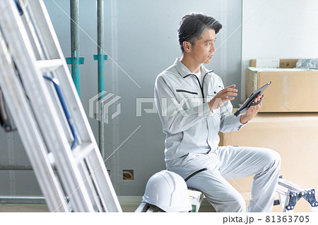 建築現場でタブレットを見ながら確認作業をする現場監督 81363705