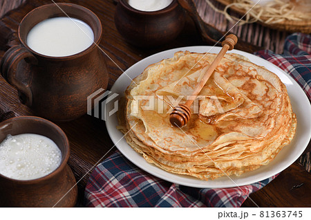 A stack of thin pancakes with honey on a wooden board. A stack of thin pancakes with honey on a wooden board. 81363745