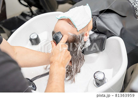 ヘアサロンでシャンプーをしてもらう若い女性 81363959