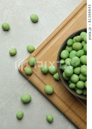 Board with bowl of wasabi nuts on white textured background Board with bowl of wasabi nuts on white textured background 81366643