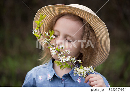 Cute little girl inhaling the aroma of cherry flowers in a park Cute little girl inhaling the aroma of cherry flowers in a park 81367444