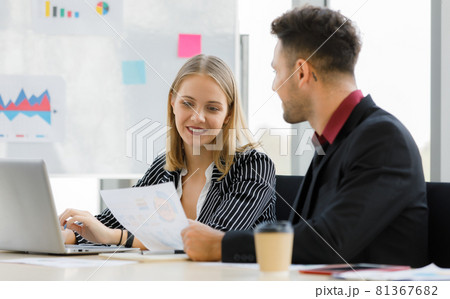Portrait of adults caucasian 1 businessman holding report graph paper and 1 businesswoman using laptop are sitting, talking and smiley with sticky paper in blur background during a meeting on morning 81367682