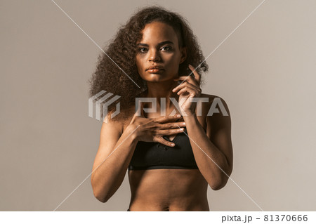 Woman power activist African American girl with afro hair standing in black bare shoulder top isolated on grey background. Human emotions, facial expression concept Woman power activist African American girl with afro hair standing in black bare shoulder top isolated on grey background. Human emotions, facial expression concept 81370666