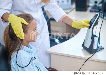 Pleased girl having her hearing checked on the audiometer Pleased girl having her hearing checked on the audiometer 81372857