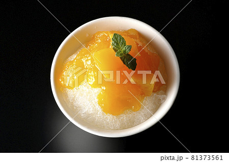 果肉入りのマンゴーシロップがたっぷりとかかったかき氷を黒背景で俯瞰撮影 果肉入りのマンゴーシロップがたっぷりとかかったかき氷を黒背景で俯瞰撮影 81373561