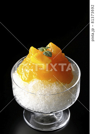 果肉入りのマンゴーシロップがたっぷりとかかったかき氷を黒背景で撮影 81373692