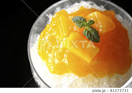 果肉入りのマンゴーシロップがたっぷりとかかったかき氷を黒背景で俯瞰撮影 果肉入りのマンゴーシロップがたっぷりとかかったかき氷を黒背景で俯瞰撮影 81373731
