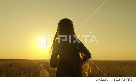 Happy girl runs in headphones at sunset, an active lifestyle for losing weight and maintaining a slim figure, a woman striving for the dream of being the first, preparing for a running competition 81373739