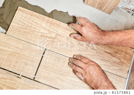 Man laying ceramic floor tiles. Close-up, selective focus Man laying ceramic floor tiles. Close-up, selective focus 81373861