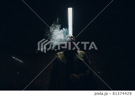 Portrait of young caucasian man smoking e-cigarette in dark with line light 81374429